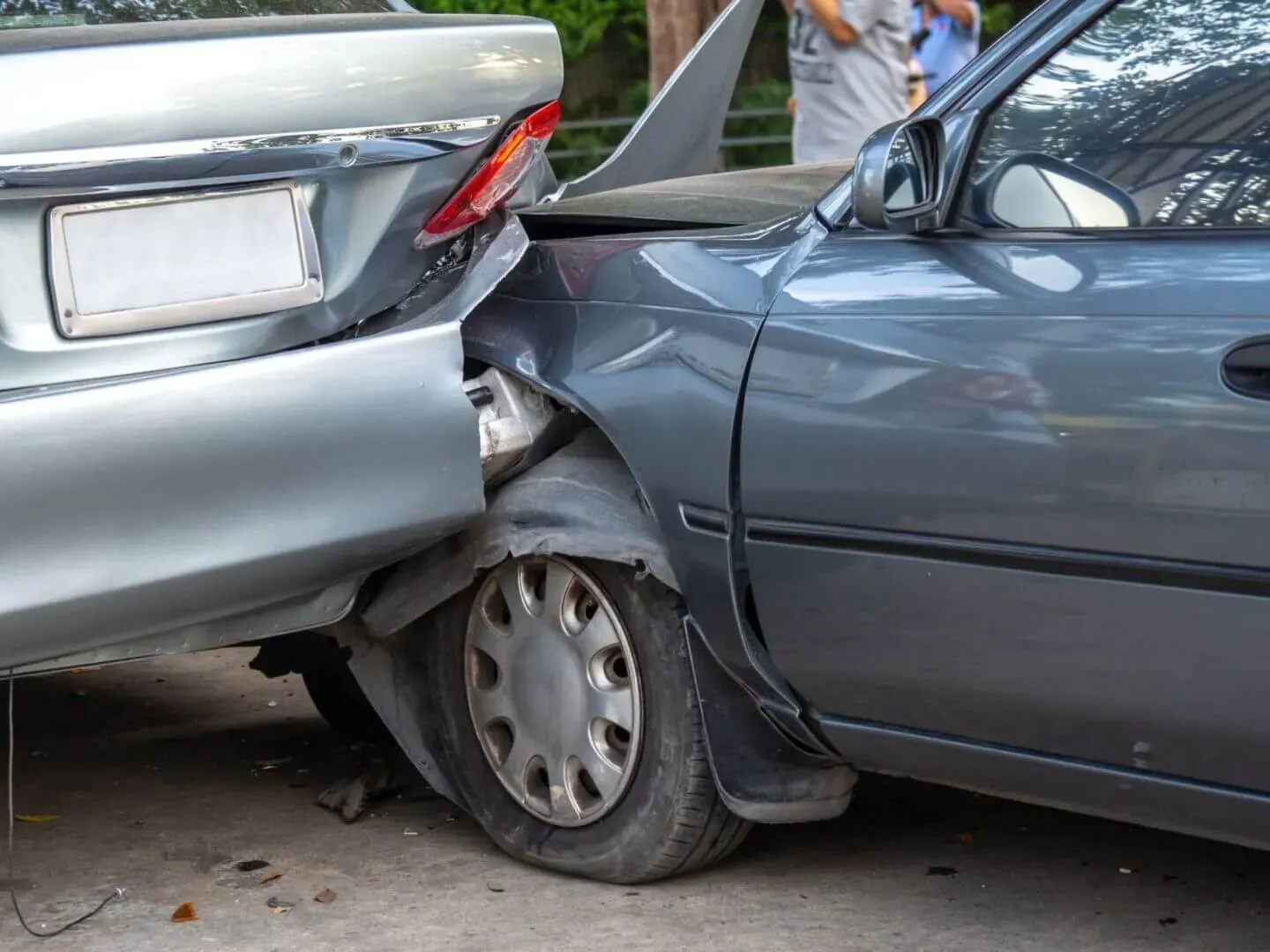 A car accident showing a dark grey car crumpled against the rear bumper of a silver vehicle.